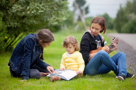 Little girl learning read and playing musical instruments outdoors, early all-round developmentの写真素材