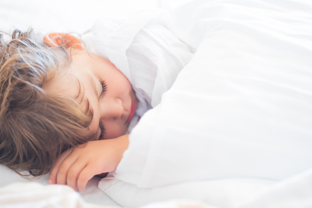 Adorable little girl lying in the bed and sleeping in the early morning, healthy sleep, easy wake up.の写真素材