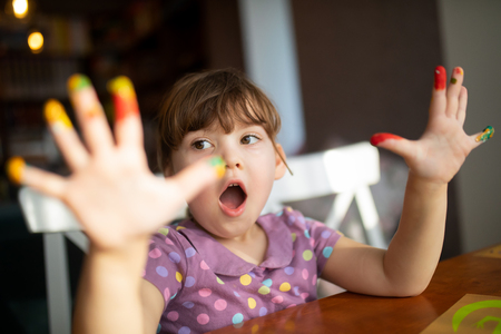 Cute little preschool gir having fun, showing her painted hands. Education, school, art and painitng conceptの写真素材