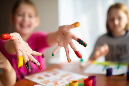 Two sisters little girls drawing with fingers on paper at home. Play, fun, childhood. Montessori...