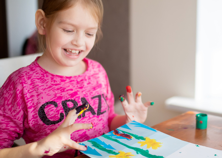 Adoranle little girl s drawing with fingers on paper at home. Play, fun, childhood. Montessori school.の写真素材