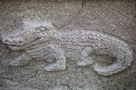 Crocodile carved in stone on the wall, old decorative ornament.
