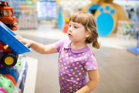 Little kid girl at the children shop, choosing toys, lifestyleの写真素材