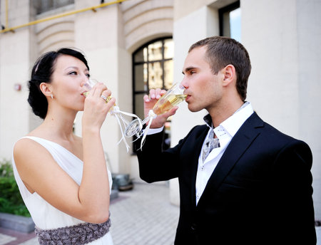 Bride and groom drinking champagne outdoor after a wedding ceremonyの写真素材