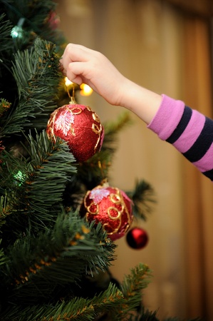 Little girl decorating the Christmas tree (focus on ball)の写真素材