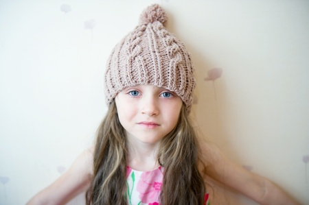 Portrait of a child girl with long hair wearing beige knitted hatの写真素材