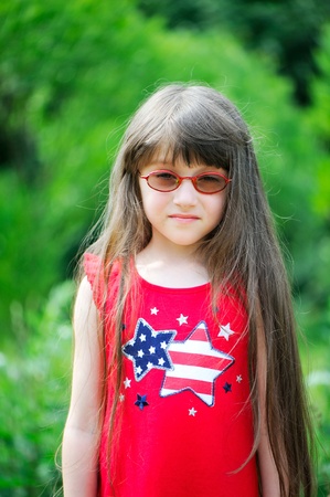 Summer portrait of brunette little girl wearing red dress with USA flag patternの写真素材