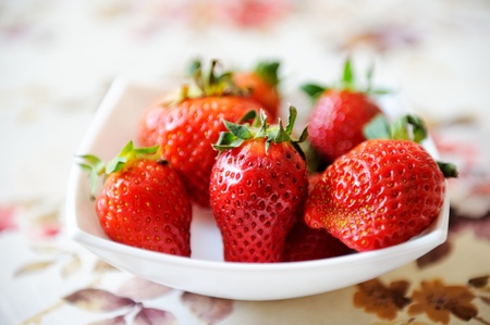 Strawberries on a plate on a table cloth backgroundの写真素材