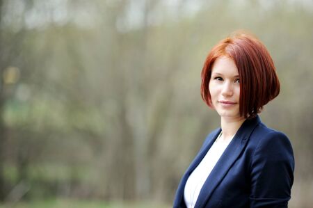 Portrait of beautiful woman with red hair posing outdoorsの写真素材