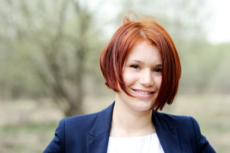 Portrait of beautiful woman with red hair posing outdoors