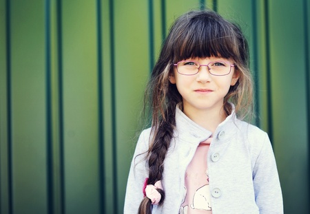 Portrait of brunette toddler girl in glasses against green wallの写真素材