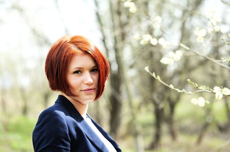 Close-up portrait of beautiful woman with red hair posing outdoorsの写真素材