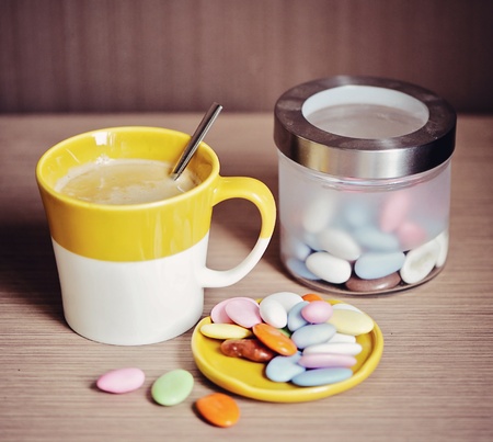 Cup of coffee, candies and glass box on wooden tableの写真素材