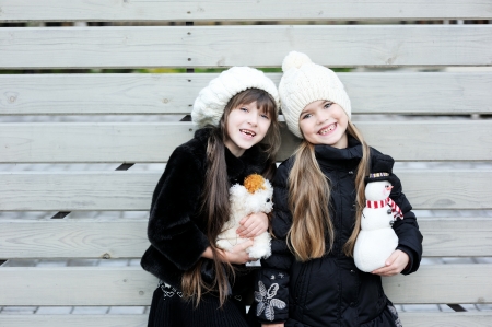 Little girls in warm outfit posing outdoors with toysの写真素材