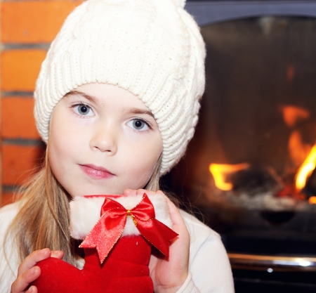 Portrait of child girl in white hat posing by the fireplaceの写真素材