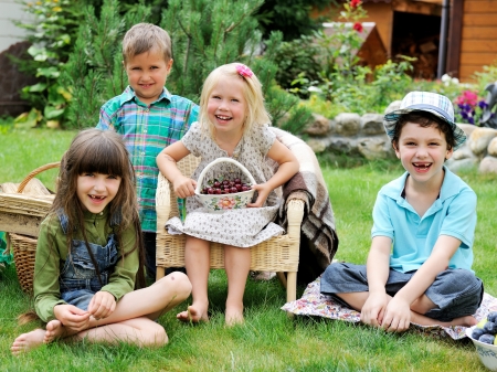 Group of happy children having picnic on a green lawn in front of country houseの写真素材