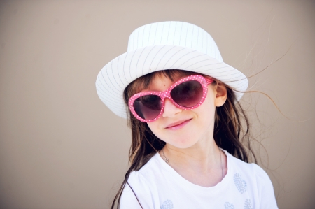 Portrait of serious little girl in white hat and sunglassesの写真素材