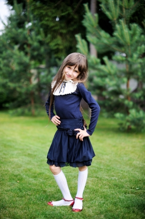 Cute school girl in navy uniform posing in a gardenの写真素材
