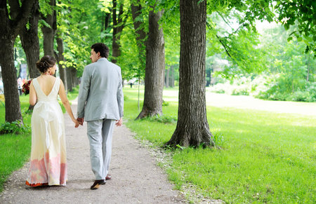 Bride and groom walking together in a parkの写真素材