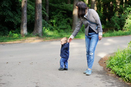Happy mother walking with her baby boy in the park