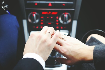 Hands of young just married  men and woman inside of a carの写真素材