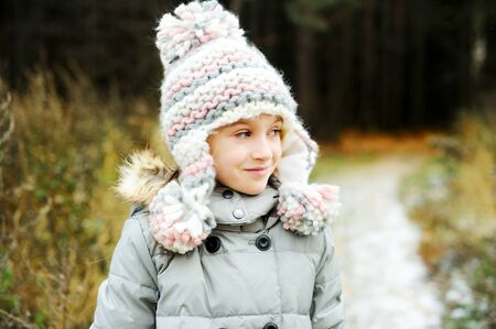 Portrait of adorable girl in grey hat, scarf and coat  outdoor in winter parkの写真素材