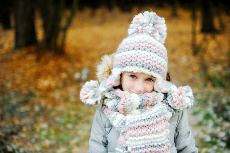 Portrait of adorable girl in grey hat, scarf and coat  outdoor in winter parkの写真素材