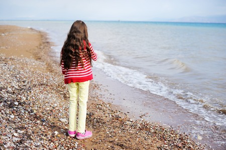 Adorable happy brunette young girl on beach vacation in the stormy dayの写真素材