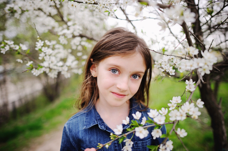 Adorable kid girl in blooming cherry garden on beautiful spring dayの写真素材