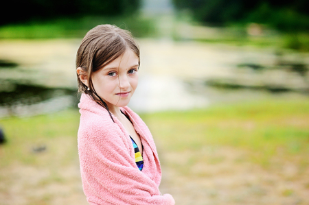 Cute little girl at river beach covered with towelの写真素材