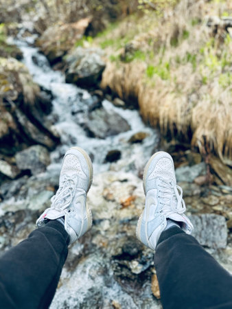 Selfie of male legs in sneakers standing on a mountain stream.の写真素材