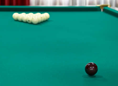 Brown ball against white balls on green tableの写真素材