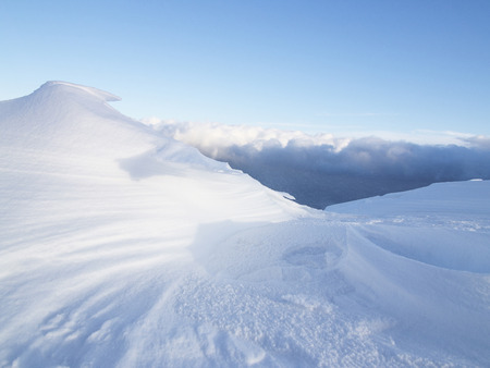 Snowdrift against a blue sky and cloudsの写真素材