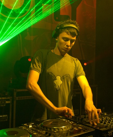 DJ works with music control panel under green laser raysの写真素材