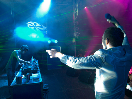 The presenter and the DJ on the stage against the laser raysの写真素材