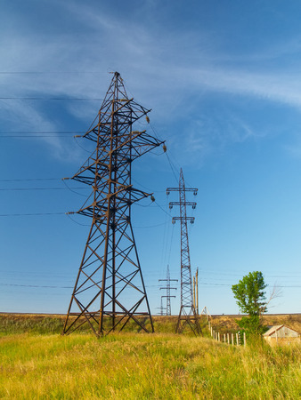 Electric power transmission lines in the field next to small houseの写真素材