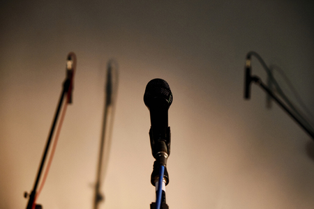 Vocal microphone and two blurred studio recording microphones with shadows against highlighted backgroundの写真素材