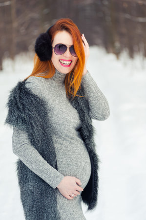Portrait of red headed pregnant woman in snowy forestの写真素材