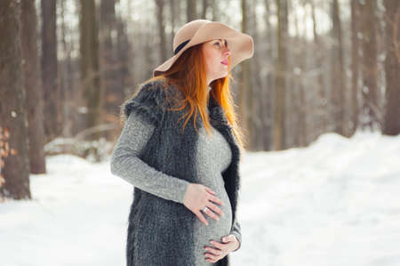 Portrait of red headed pregnant woman in snowy forestの写真素材