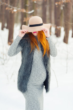 Portrait of red headed pregnant woman in snowy forest