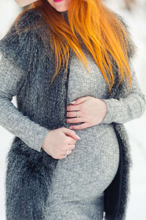 Portrait of red headed pregnant woman in snowy forestの写真素材