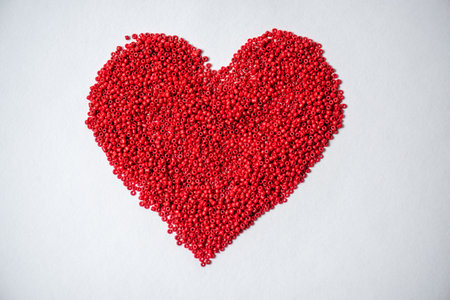 Red heart made of plastic granules on white background, top viewの写真素材
