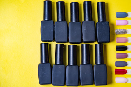 Black nail polish bottles on yellow background. Top view, flat lay.の写真素材