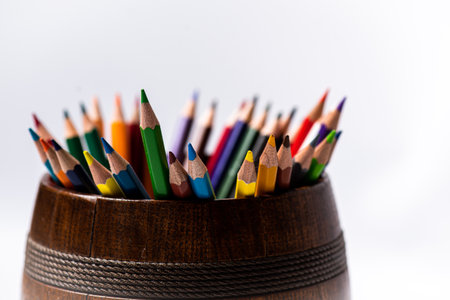 Colorful pencils in a wooden cup on a white background.の写真素材