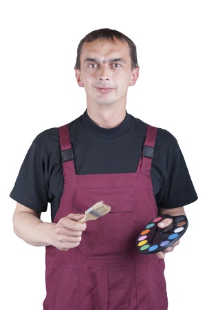 The man in the building clothes with a brush and a paint watercolors in his hands.の写真素材