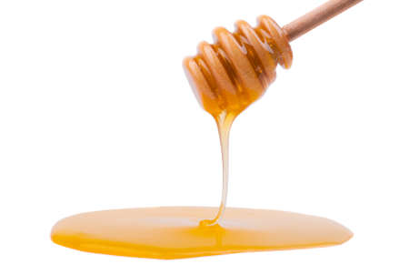 Honey dripping from a wooden spoon.の写真素材
