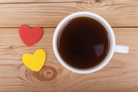 Cup of coffee and two hearts on a wooden background.の写真素材