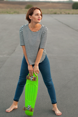 Girl with skateboard standing barefoot on the asphalt.の写真素材
