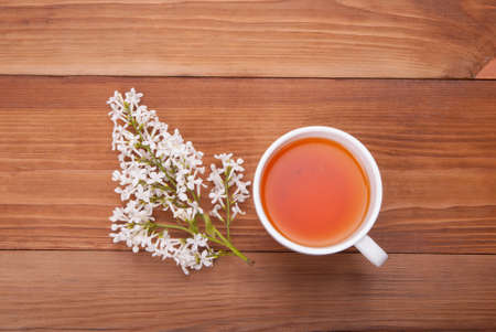 Cup of tea and a bouquet of lilacs on a wooden background.の写真素材
