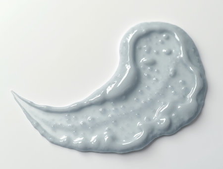 A soft gray paint is artistically spread across a clean white surface, revealing its smooth texture and glistening sheen. The scene captures a moment in a creative workspace.の素材